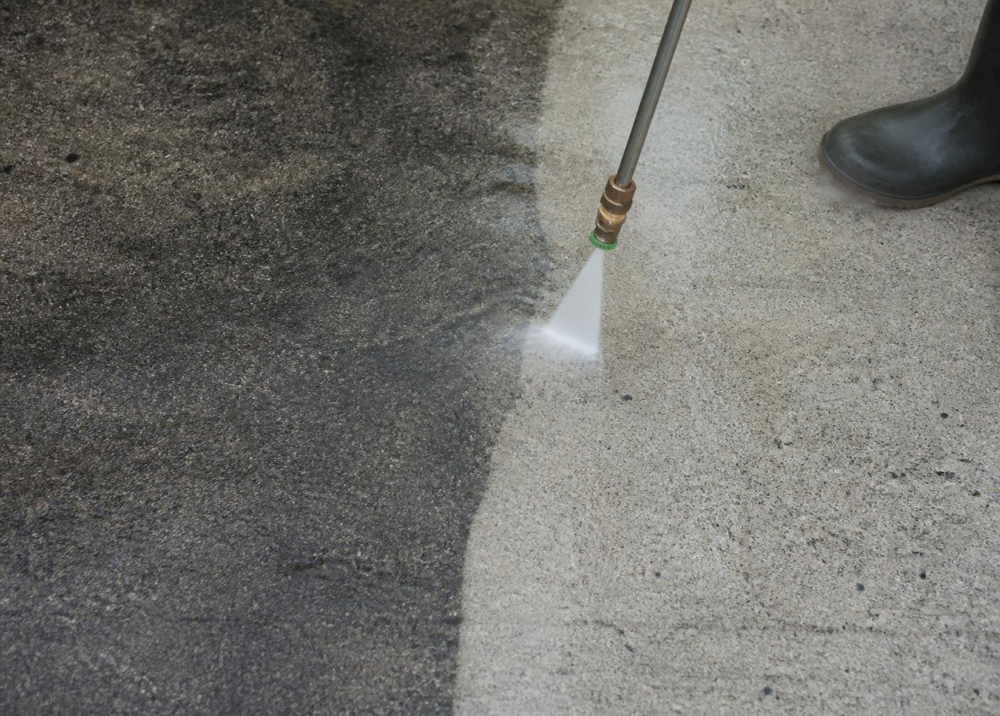 High-pressure cleaning restoring a stained concrete driveway