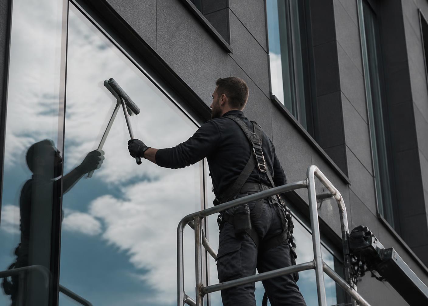 Technician cleaning glass on a modern commercial building